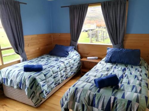 two beds in a room with a window at Vista al Paine - Refugio de Aventura in Torres del Paine