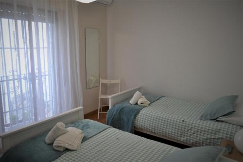 two beds in a room with a window and towels at Guimar Esencia en el corazón de la judería in Córdoba