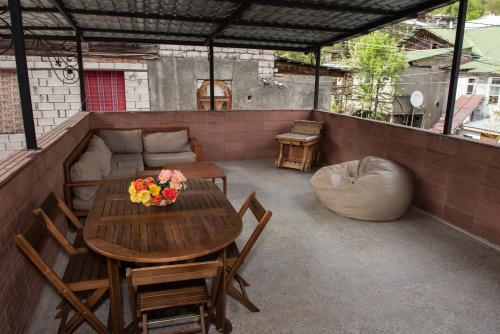 un patio con mesa, sillas y sofá en Guest House VIP, en Borjomi