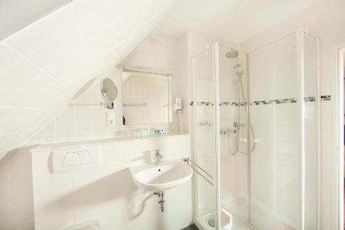 a white bathroom with a sink and a shower at Ferienhotel Bernstein in Trassenheide