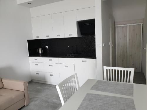 a kitchen with white cabinets and a table and a couch at Apartamenty Zełwągi in Mikołajki