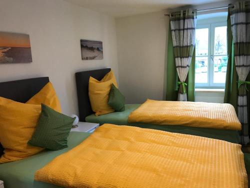a room with two beds with yellow and green pillows at Gästehaus Sarker in Landsberg am Lech