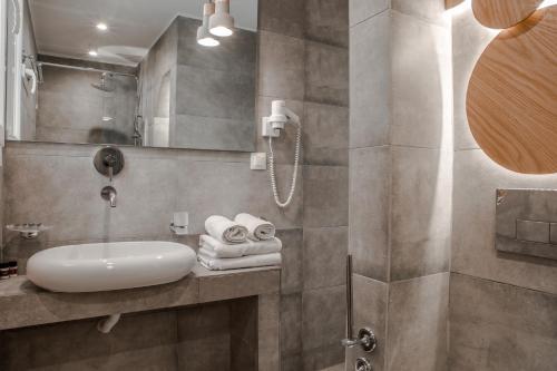 a bathroom with a sink and a shower with towels at Blue Bay Resort Village in Batsi