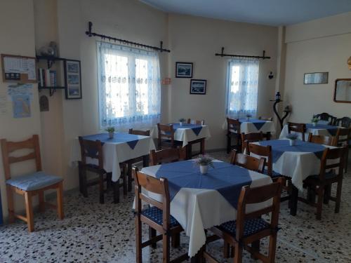 a dining room with blue tables and chairs and windows at Villa Firostefani in Firostefani