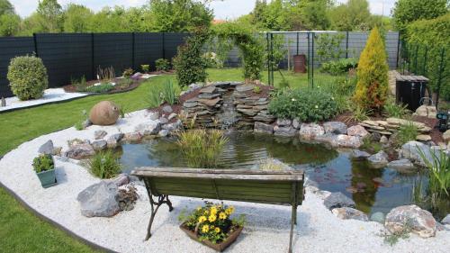 a park bench in a garden with a pond at studios les Hortensias in Lillers