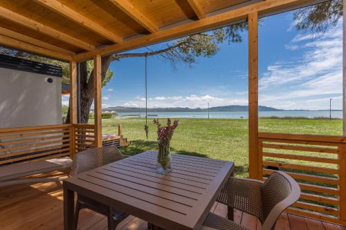 a table on a porch with a view of a field at Camp Vransko lake - Mobile homes in Pakoštane