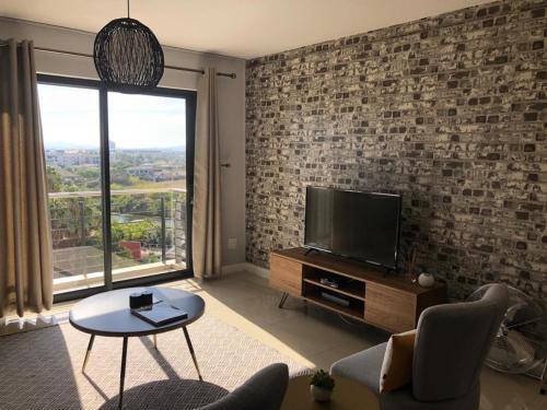 a living room with a flat screen tv on a brick wall at Home relaxation in the city in Cape Town