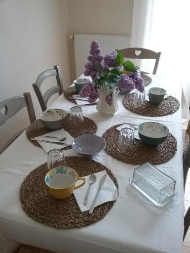 a table with plates and bowls and a vase of flowers at Au Nid Douillet in Seigy