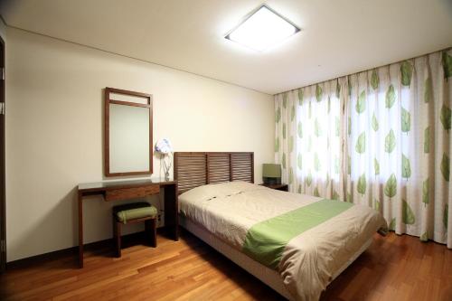 a bedroom with a bed and a desk and a mirror at Hanwha Resort Jeju in Jeju