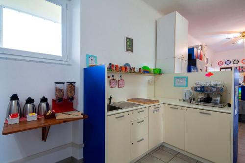 eine Küche mit weißen Schränken und einem blauen Kühlschrank in der Unterkunft Ostello Corniglia in Corniglia