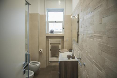 a bathroom with a toilet and a sink and a window at Parini Flat in Lecce