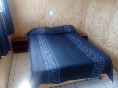 un letto con piumone blu in una camera di Cabaña tablaqui a El Quisco