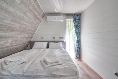 a white bed in a room with a window at Zen Garden Resort, Zánka in Zánka
