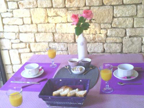 una mesa púrpura con una bandeja de bollería y zumo de naranja en Le Clos Gaillardou, en La Roque-Gageac