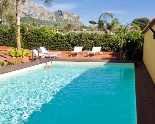 een zwembad met stoelen en bergen op de achtergrond bij La Caletta Casa Vacanze, PRIVATE POOL in Terrasini