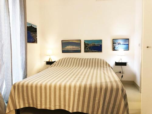 a bedroom with a bed and three paintings on the wall at Il Teatro in Scilla