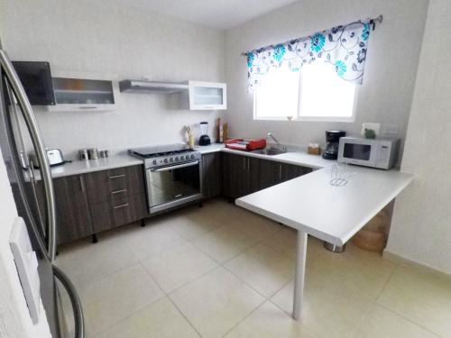 a small kitchen with a stove and a microwave at PlayaTurquesa Moderna Casa C/R Auto a 9 min 5ta ave in Playa del Carmen