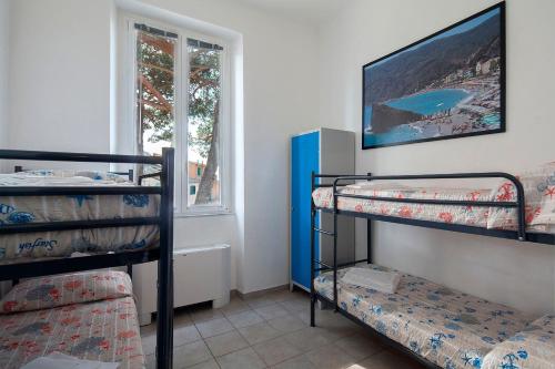 Zimmer mit 3 Etagenbetten und einem Fenster in der Unterkunft Ostello Corniglia in Corniglia