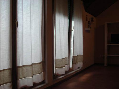 una camera con due finestre con tende bianche di FARO TRILOCALE PIANO ATTICO a Lignano Sabbiadoro