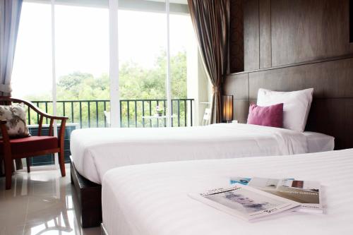 a hotel room with two beds and a balcony at Lub Sbuy House Hotel - SHA in Phuket Town