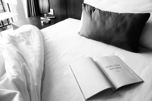 a book sitting on top of a bed with a pillow at Lub Sbuy House Hotel - SHA in Phuket Town