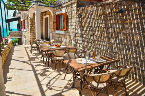 a patio with tables and chairs and a stone wall at Villa Marinero in Ulcinj