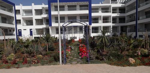a garden with flowers in front of a building at Appartement Agadir Awrir in Agadir