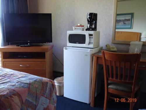 a microwave on top of a refrigerator next to a television at Hospitality Inn in Kamloops