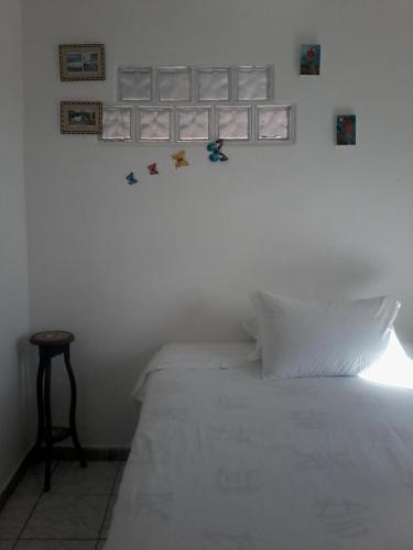 a bedroom with a white bed with pictures on the wall at Suítes Novo Amanhecer in Sao Jorge