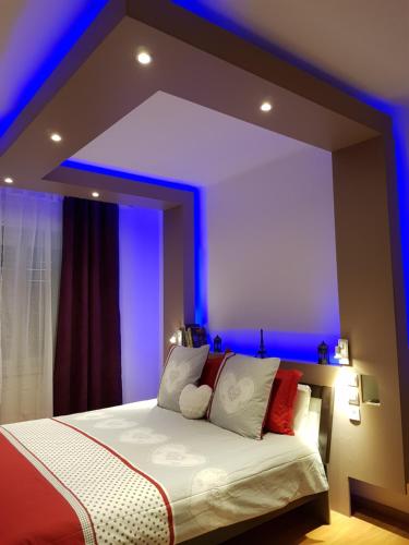 - une chambre dotée d'un grand lit avec des lumières bleues dans l'établissement le wineck, à Colmar