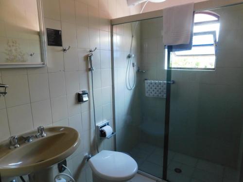 a bathroom with a shower and a toilet and a sink at Hotel Real São Lourenço in São Lourenço