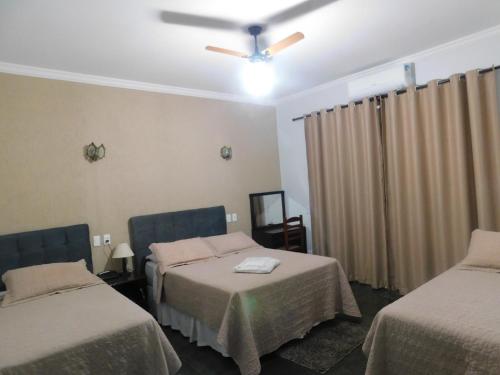 a room with two beds and a ceiling fan at Hotel Real São Lourenço in São Lourenço