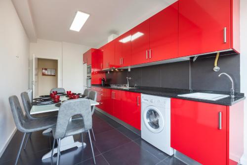 a red kitchen with a table and a washing machine at Feel at home - Free private parking in Braga
