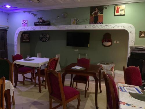 a dining room with a table and chairs and a tv at Gya-son Royal Guest House in Kumasi