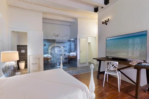 a bedroom with a bed and a desk with a large screen tv at Cagliari Marina Harbour Guest house & Lounge in Cagliari