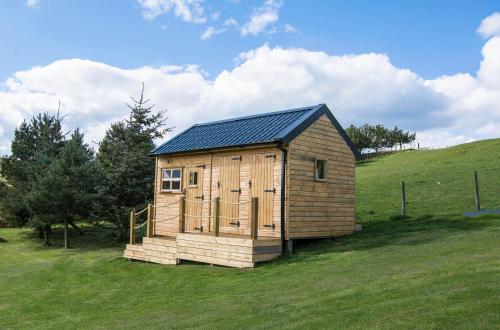 a small wooden cabin in a field of grass at Little Lochan Lodge in Glenfarg