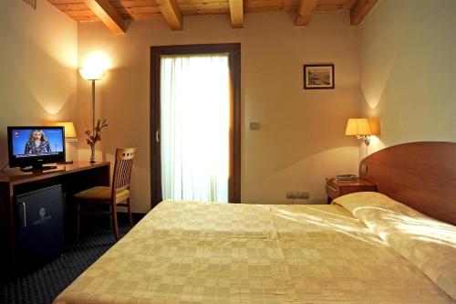 una camera con letto, scrivania e TV di Hotel Vittoria a San Giórgio di Nogaro