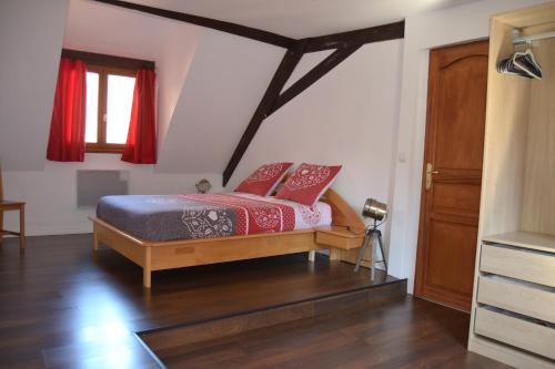 - une chambre avec un lit doté de rideaux rouges et d'une fenêtre dans l'établissement P'tit Biscuit, à Riquewihr