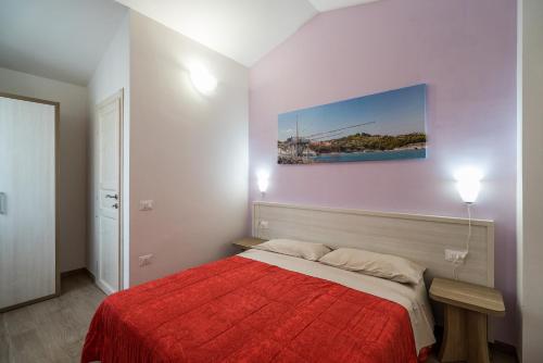 a bedroom with a red bed and a painting on the wall at La Duchessa e Il Contadino in Vieste