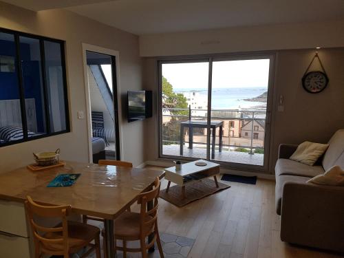 - un salon avec une table et une vue sur l'océan dans l'établissement Kerwelmor, appartement avec vue sur la mer, à Saint-Quay-Portrieux