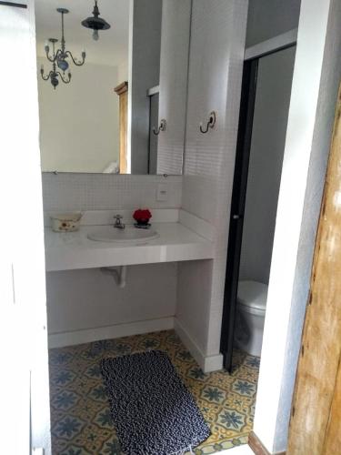 a bathroom with a sink and a mirror and a toilet at Pousada da Bia in Tiradentes