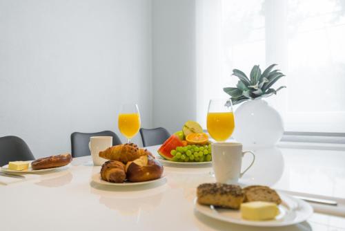 a table with plates of food and two glasses of orange juice at Olive gardens in Primošten