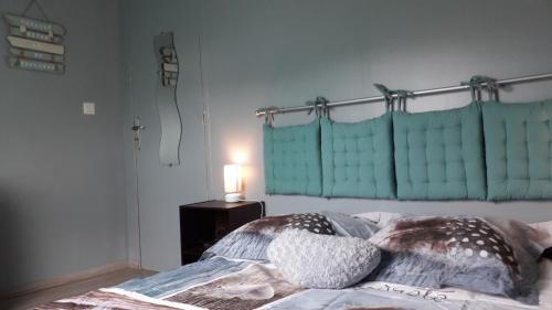 ein Bett mit zwei Kissen und einer Lampe auf einem Tisch in der Unterkunft ENFIN ! in Grandcamp-Maisy