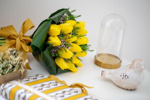 a table with a bouquet of yellow flowers and a bottle at Domus Duorum in Porto