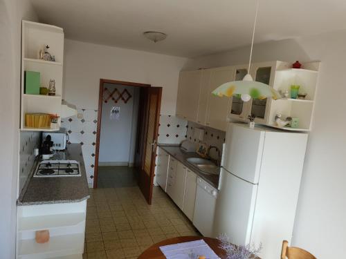 a kitchen with white cabinets and a white refrigerator at Apartman Dora in Šmrika