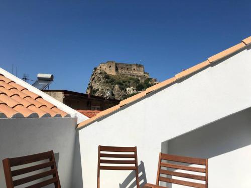 two chairs on a roof with a castle in the background at Il Castello in Scilla