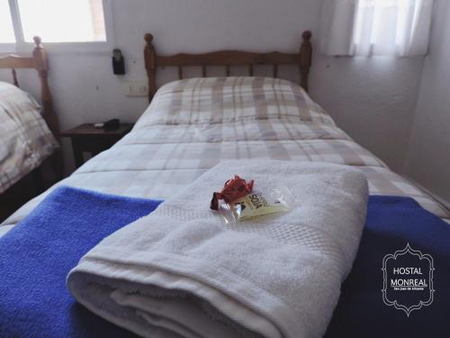 Una cama con toallas blancas y un juguete. en HOSTAL MONREAL, en San Juan de Alicante