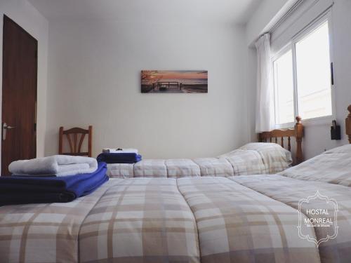 サン・ホアン・デ・アリカンテにあるHOSTAL MONREALのベッドルーム1室(ベッド2台、窓付)