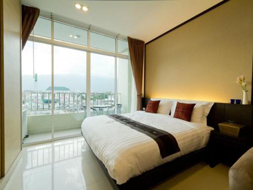 a bedroom with a large bed and a large window at The Grand Wipanan Residence in Chiang Mai