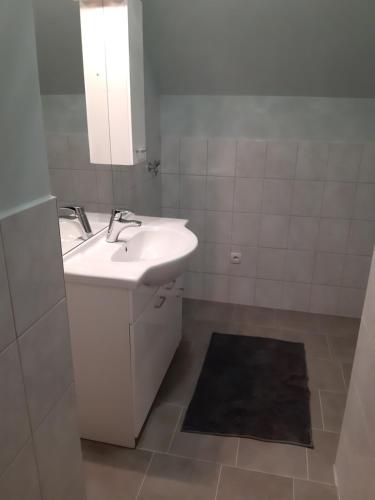 ein weißes Badezimmer mit einem Waschbecken und einem Spiegel in der Unterkunft Privatzimmer Roland in Hutten